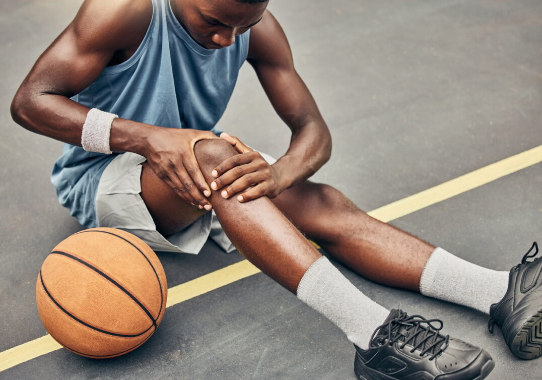 Young basketball player holding injured knee