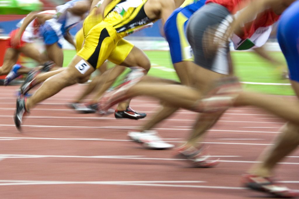 Image of 100 meters athletes in action with intentional blurring.